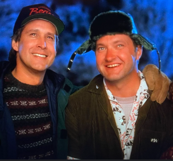 Cousin Eddie arrives just in time to see Clark's house lighting. They stand side by side. A scene from "National Lampoon's Christmas Vacation." One of the best funny Christmas movie quotes.