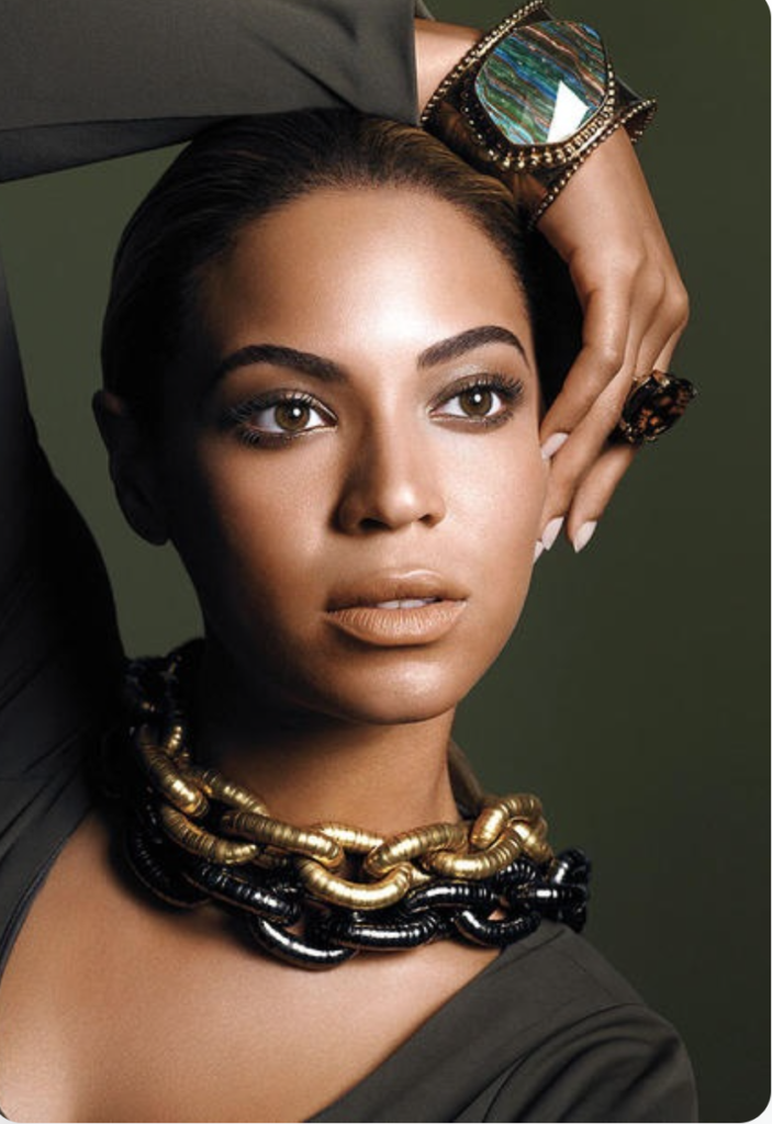 a picture of Beyonce with beautiful chunky jewelry and hand over her head