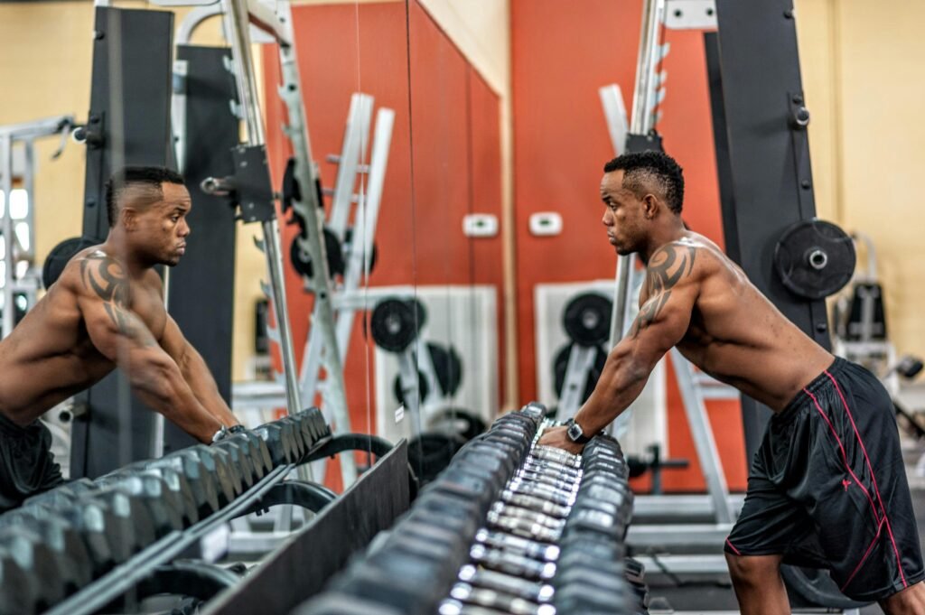 Tighten skin by strength training- a man stands at the dumbbell section of the gym preparing to lift weights
