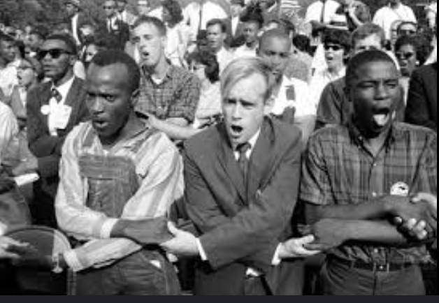 a black and white image of blacks and whites interlocking hands as they sing together in protest