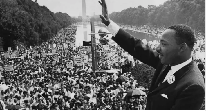 a black and white picture of Dr. Martin Luther King Jr. at the Lincoln Memorial, 1963 waving to the huge crowd