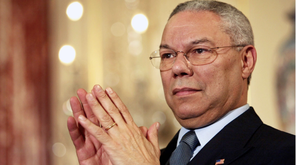 a headshot of Secretary of State Colin Powell listening to a speech with fingertips touching and a focused look