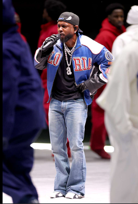 Inspirational quotes for young black males -- an image from Kendrick Lamar's Super Bowl halftime performance wearing a custom leather jacket, Celine jeans, Nike Air sneakers. He is surrounded by his dancers wearing either solid red, white, or blue jumpsuits