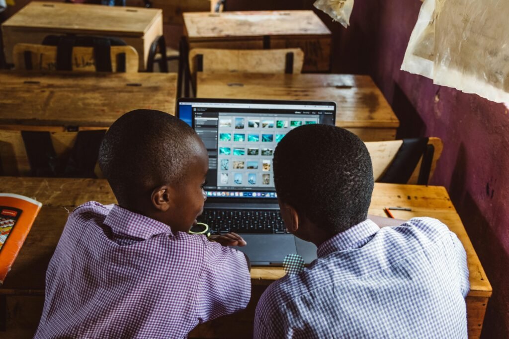 inspirational quotes for young black males: the backs of the heads of 2 young African American boys sit in front of a laptop screen (rear view)
