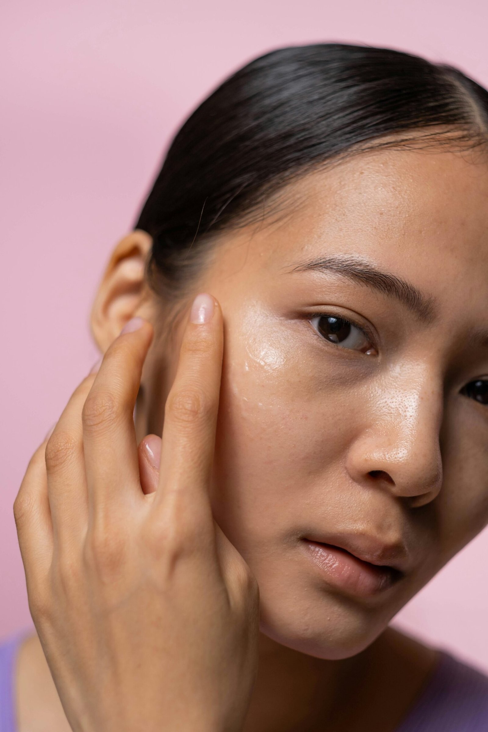 an Asian woman puts a dab of moisturizer on her "glass skin" face