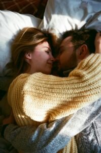 cute good morning love quotes for him - a man and woman together in bed, fully clothed, hugging each other, with the sunlight coming through window