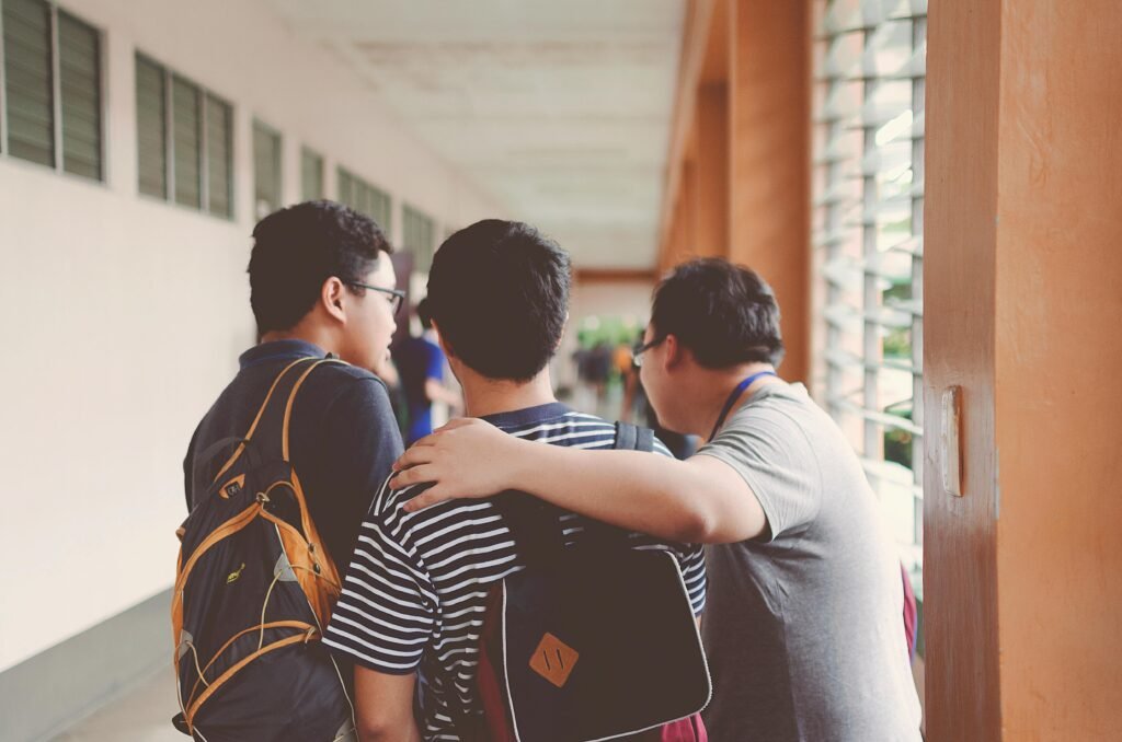 best backpacks for middle school - the backs of 3 students are shown standing in a school corridor wearing 3 different backpacks