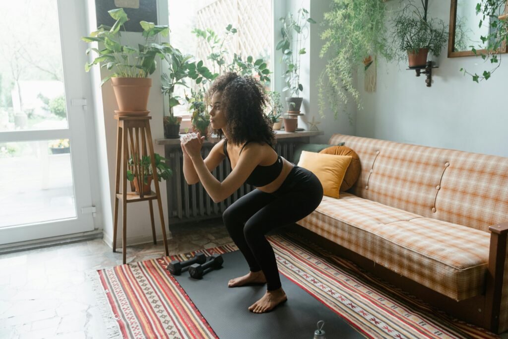 a woman performs "Squat to Stand" in her living room using a couch. This compound movement activates large muscle groups in your lower body.