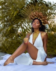 affirmations for goddess energy - a woman sits on a white sheet wearing a white toga dress and a gold sunlike crown