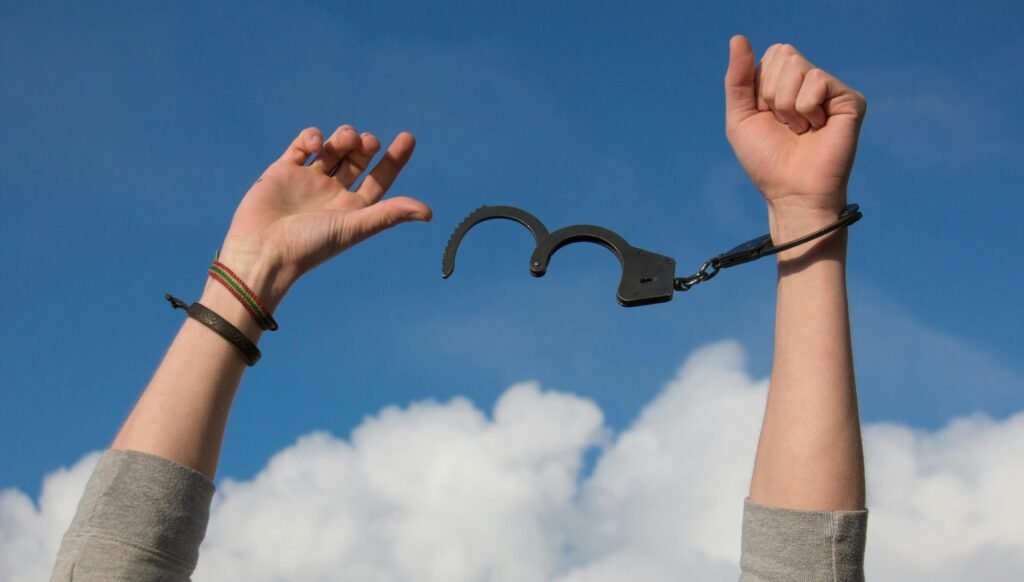 Limiting beliefs holding you back - an image of 2 arms in the air breaking free from a handcuff representing freedom