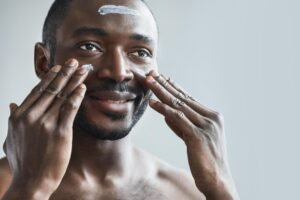 best restorative face cream - a man moisturizes his skin while looking in a mirror