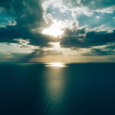 30 Day Blog Challenge - an image that represents serenity. An ocean, overall dark scene including the sky with a sliver of sun beaming off the ocean water
