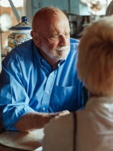 What Morning Habits Increase Dementia? an image of an elderly man who looks bothered by his thoughts as his partner sits across from him