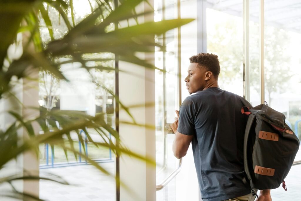 an side profile image of a student exiting the building with his backpack on