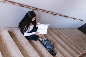first day of school activities- a young girl sits in a stairwell of her school reading
