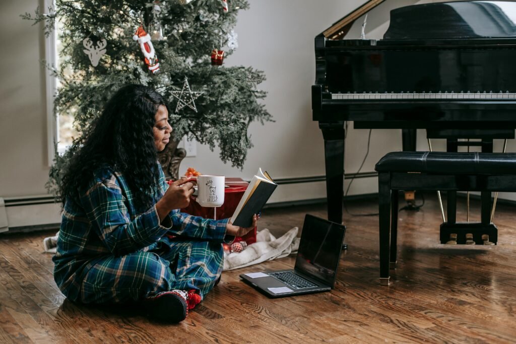 woman practicing winter self care in her pajamas with warm tea all while seated on the floor reading a book